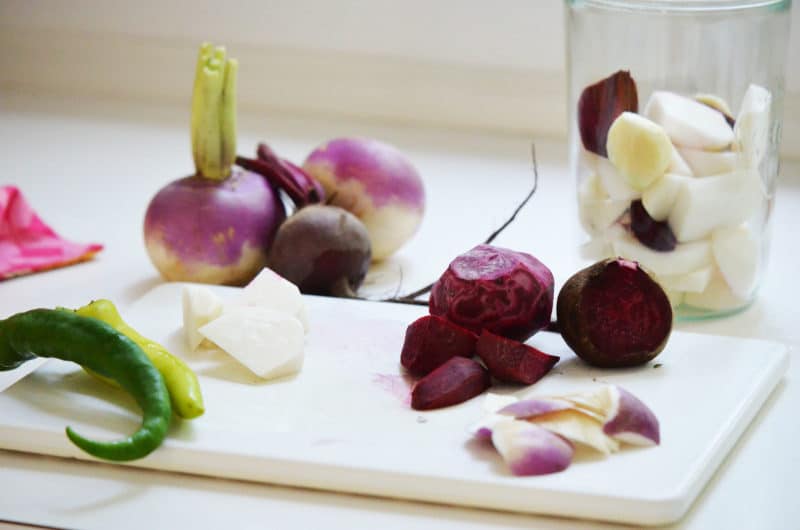 beets, turnips, jalepeño peppers on a cutting board with jar