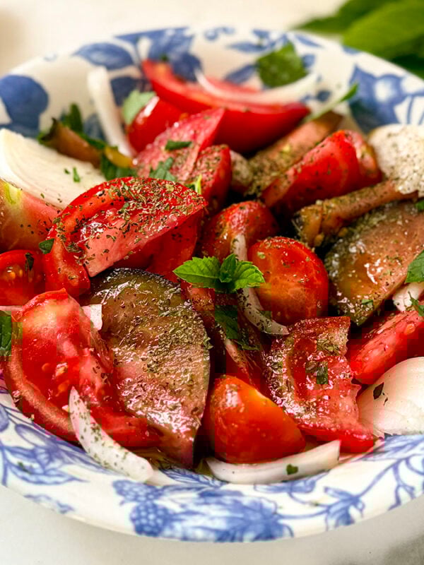 Tomato Salad in a blue and white bowl with mint on the side