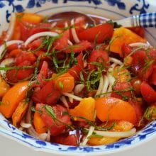 Red and yellow tomatoes with onion and mint in a blue salad bowl