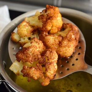 golden brown fried cauliflower in a slotted spoon