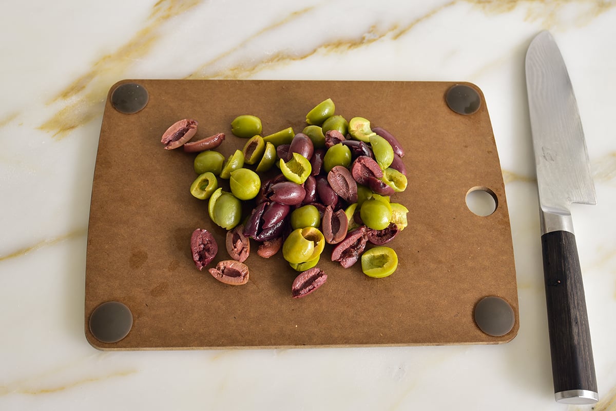 Chopped olives on a cutting board with a knife on the side