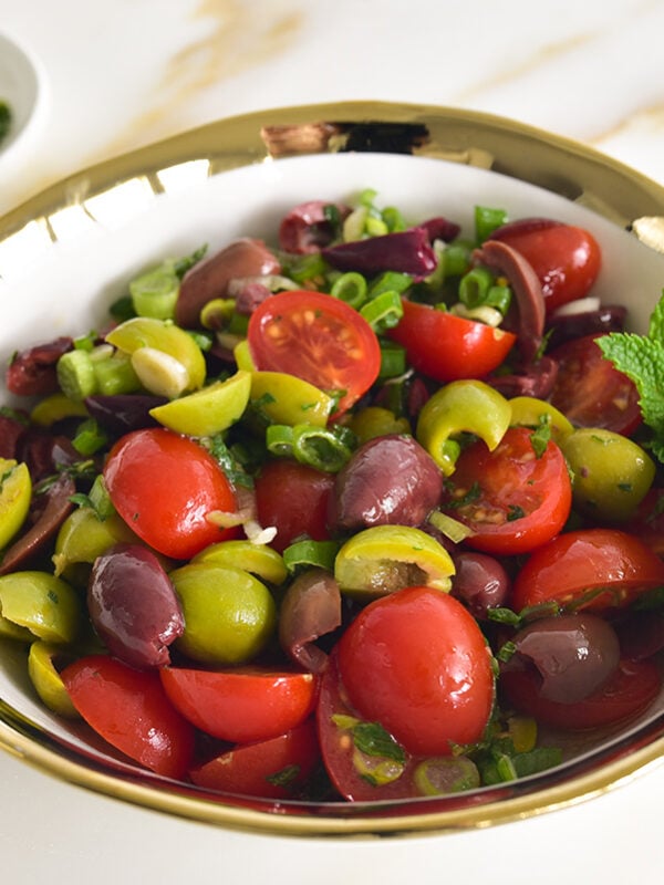 olive salad with tomatoes and mint in a gold-rimmed bowl