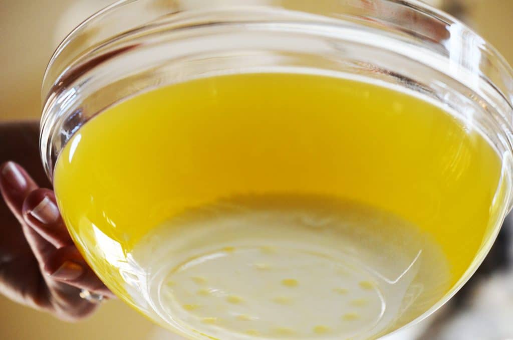 A bowl of clarified butter from the bottom view with the milk solids settled at the bottom of the glass bowl