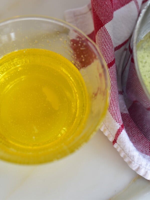 golden clarified butter in a glass bowl next to a pan and red and white towel