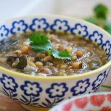 Lentil soup in a blue flowered bowl with green herbs on top