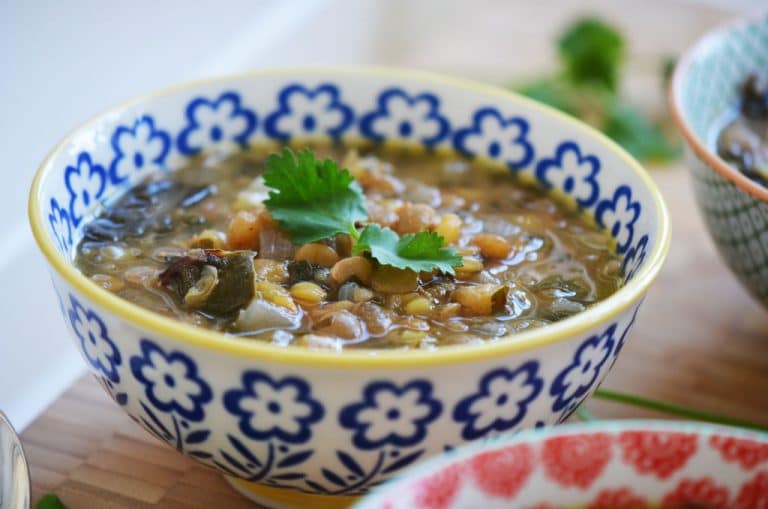 Lentil soup in a blue flowered bowl with green herbs on top