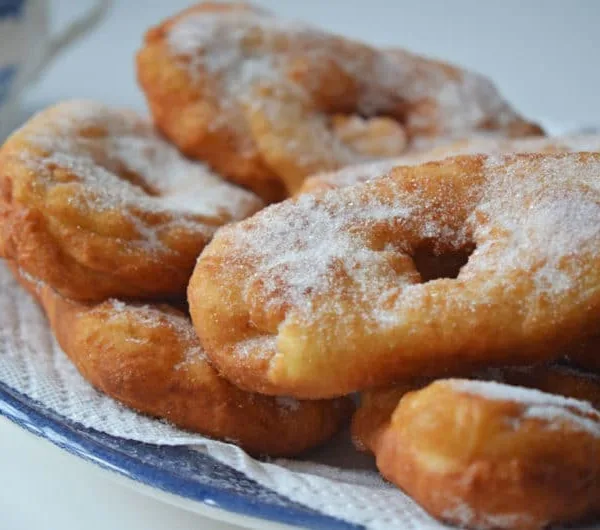 Lebanese sugared donuts on a blue plate lined with a paper towel.