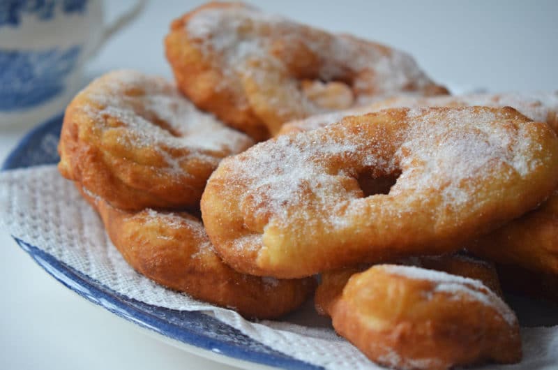 Lebanese sugared donuts on a blue plate lined with a paper towel.