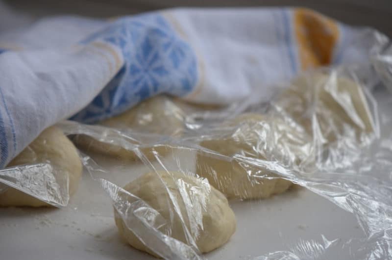 Lebanese donut dough resting uner a piece of plastic wrap.