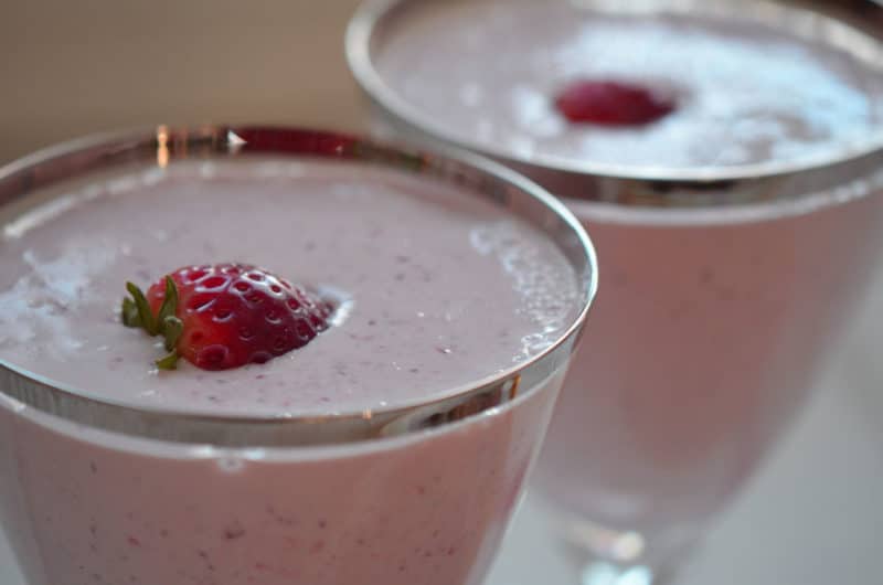 Close up shot of two glasses of strawberry shake with a slice of strawberry floating on top.