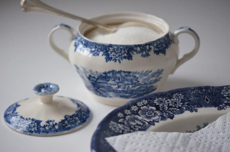 A ceramic pot of sugar with the lid resting next to it.