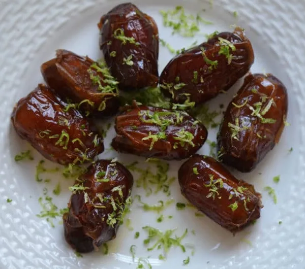 Warm Almond Stuffed Dates with Lime Zest on a round white plate
