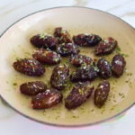 Dates topped with lime zest and sea salt in an enameled saute pan