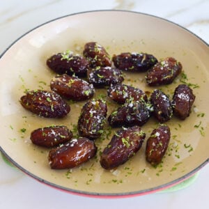 Dates topped with lime zest and sea salt in an enameled saute pan