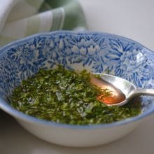 mint sauce in a blue bowl on a white surface with a spoon