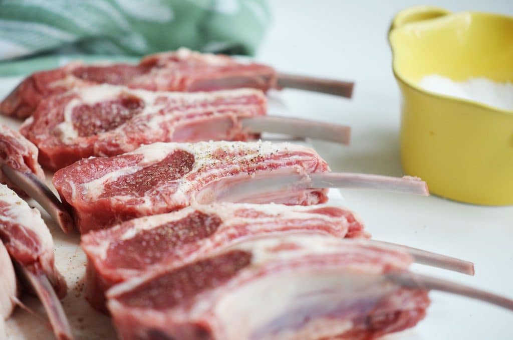 lamb chops on a board with a yellow bowl beside them