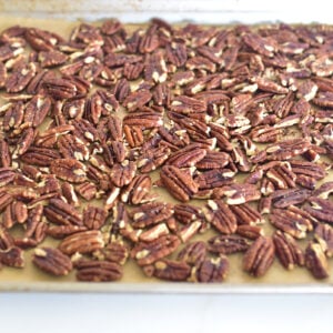 Toasted pecans on a baking sheet lined with parchment paper