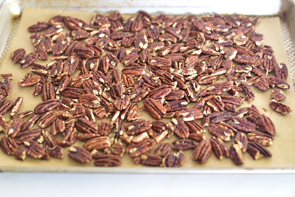 Toasted pecans on a baking sheet lined with parchment paper