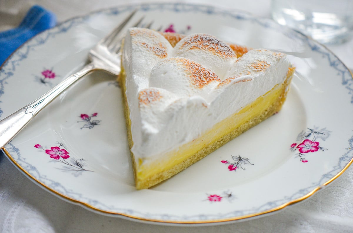 A slice of lemon meringue tart on a flowered plate