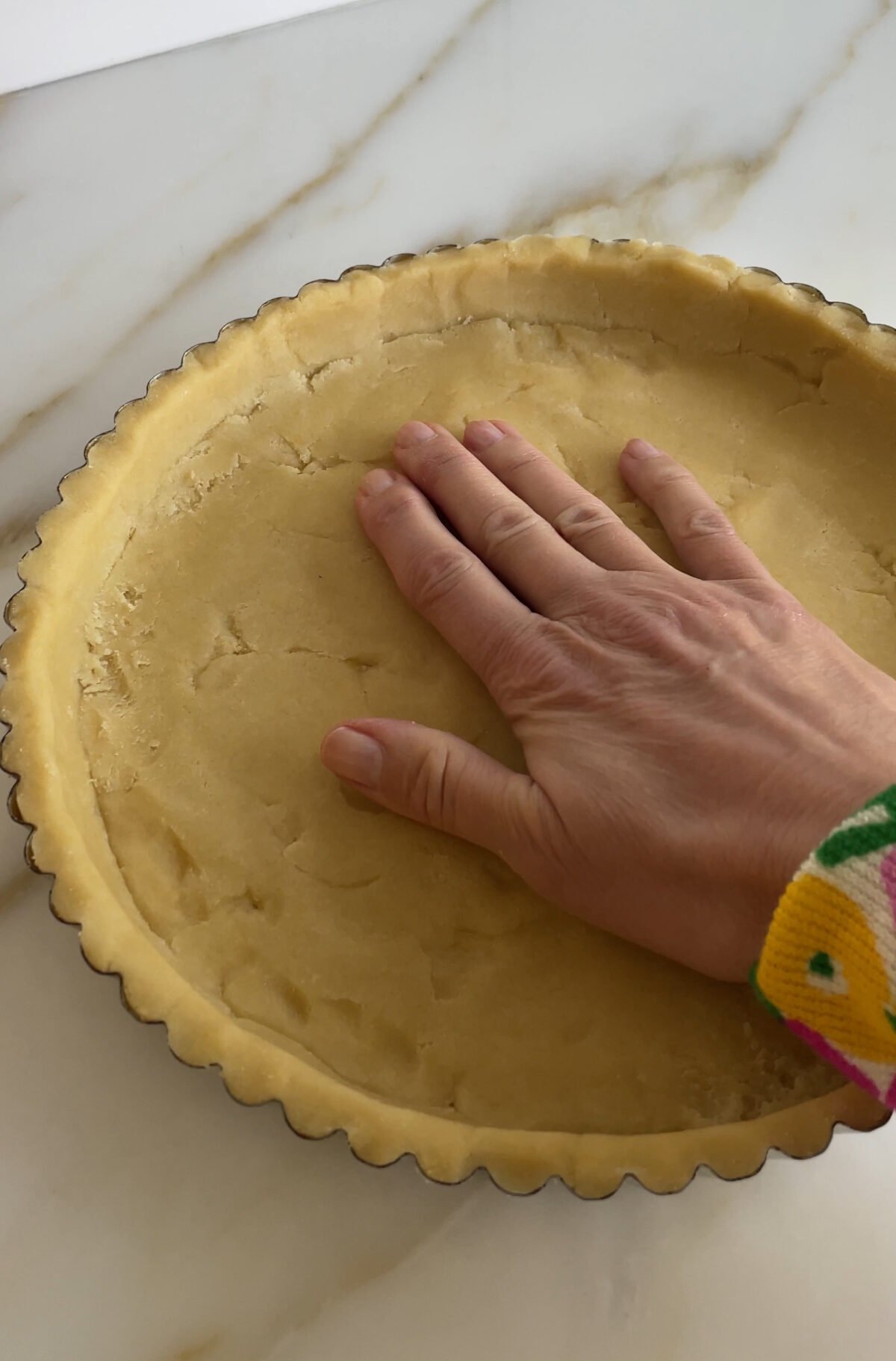 a hand pushes tart crust dough into a tart pan