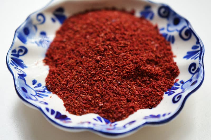 Sumac in a white and blue dish on a white surface.