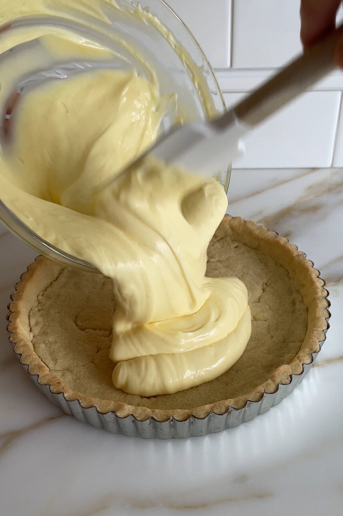 lemon filling pouring into a baked tart crust