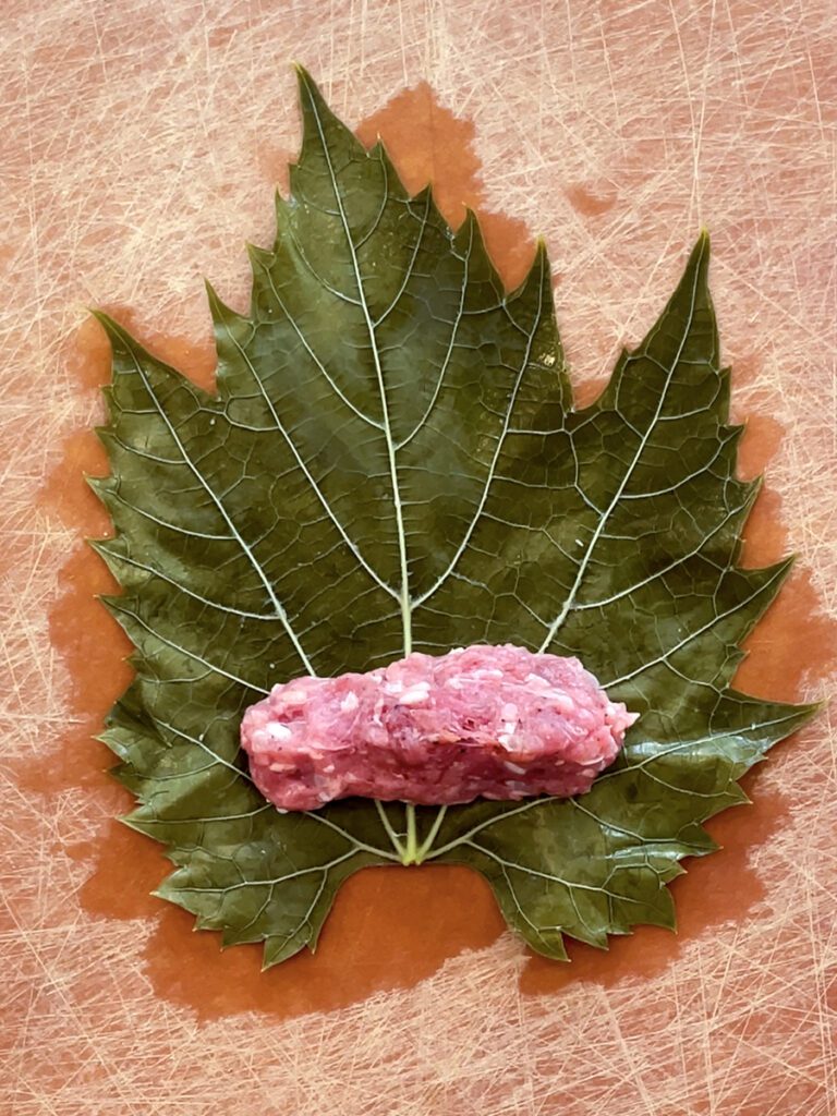 Grape leaf with meat and rice mixture across the leaf
