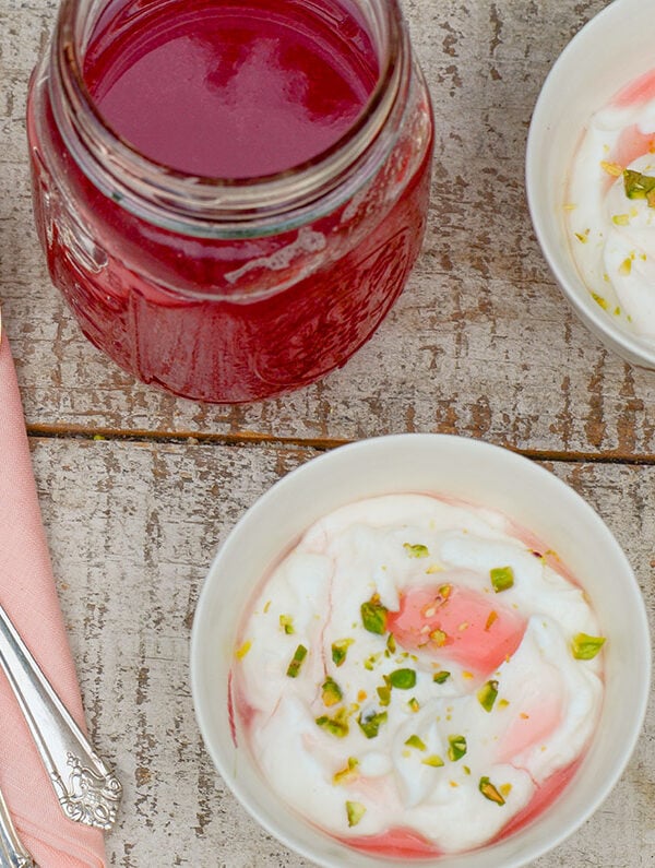 Rhubarb syrup in a jar with bowls of yogurt and syrup