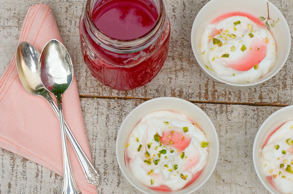 Rhubarb syrup in a jar with bowls of yogurt and syrup
