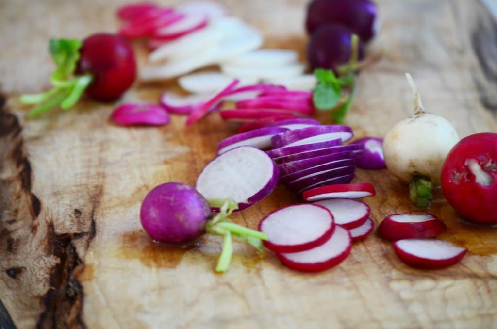 sliced radishes on a wood cutting board