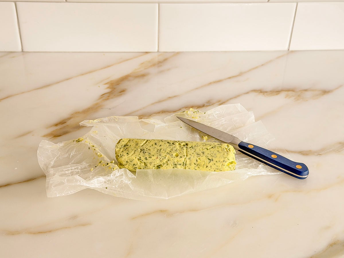 Chilled compound butter in a log with a blue knife on the side