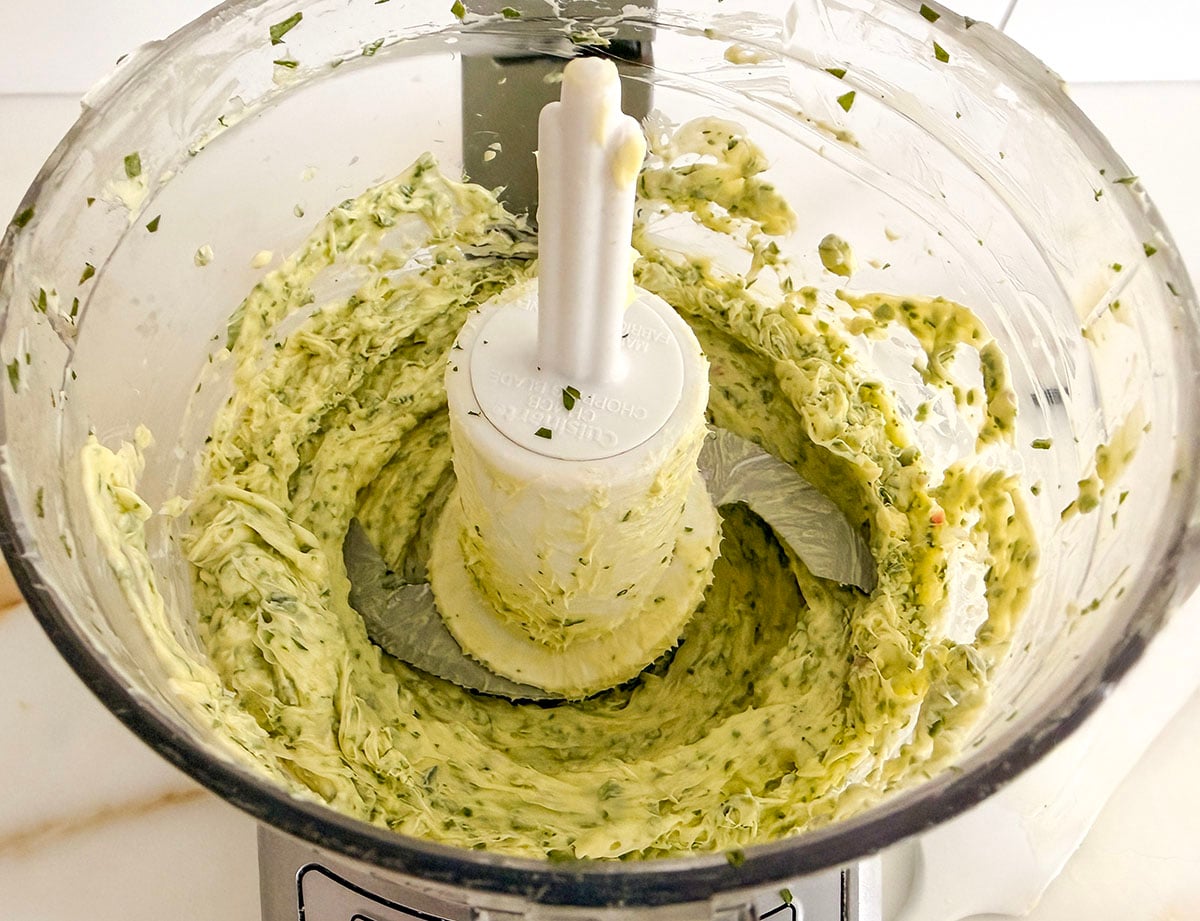 A food processor with butter and herbs processed in it