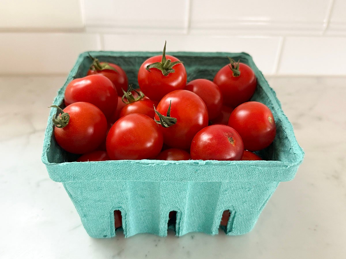 Red cherry tomatoes in a green cardboard quart