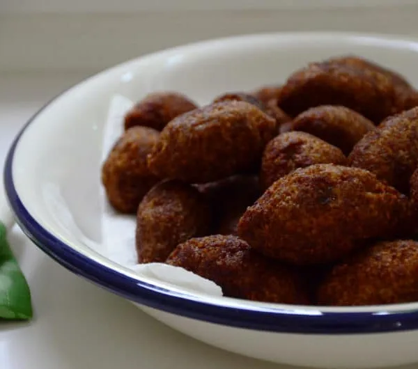 Kibbeh Footballs piled on a white platter with blue trim