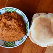 Roasted Red Pepper Dip in a bowl with pita bread on a wood table