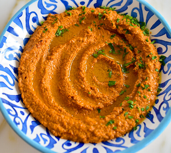 Roasted red pepper dip swirled in a blue and white bowl