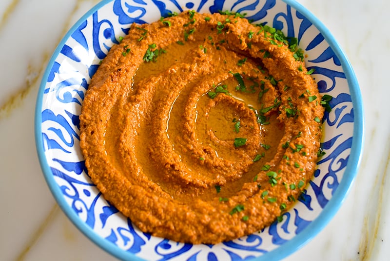 Roasted red pepper dip swirled in a blue and white bowl