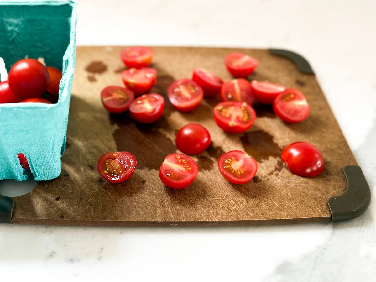 sliced cherry tomatoes on a brown cutting board