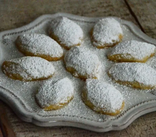 Diamond-shaped butter cookies with powdered sugar on a round plate