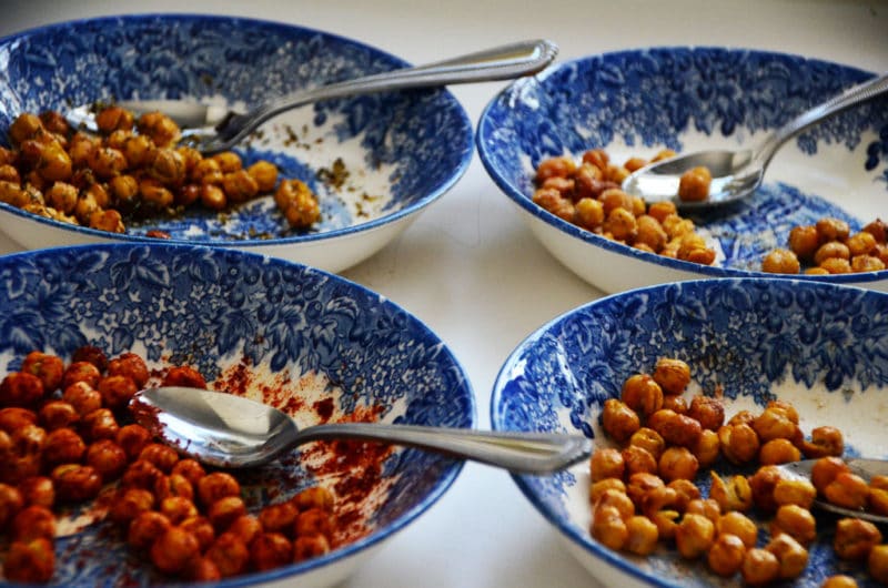 Four blue bowls with different flavors of roasted chickpeas in each bowl.