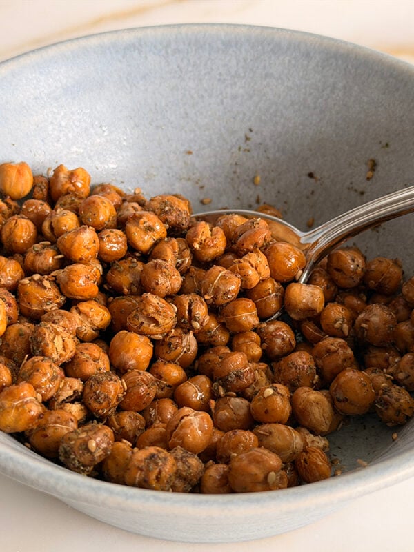 Crispy roasted chickpeas in a blue bowl with a spoon