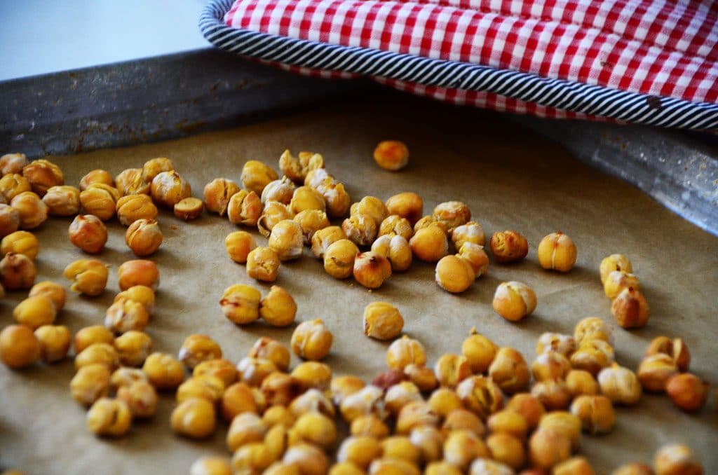 Chickpeas on a sheet pan with a red checkered hot pad