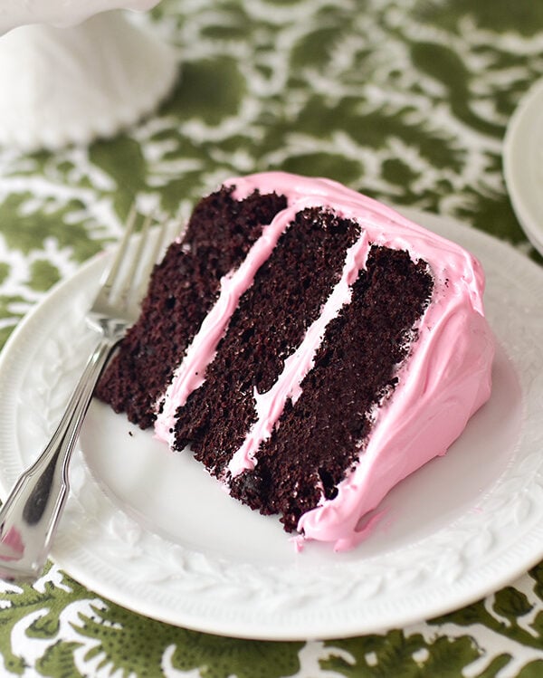 Double chocolate cake slice on a white plate with a fork on a green and white tablecloth