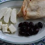White cheese cut in slices on a plate with bread and olives