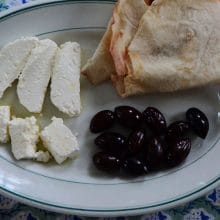 White cheese cut in slices on a plate with bread and olives