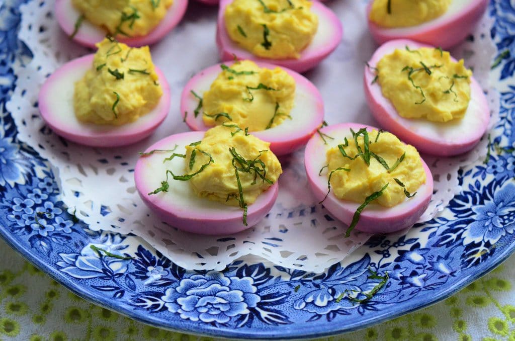 Deviled eggs on a blue plate lined with a doilie.