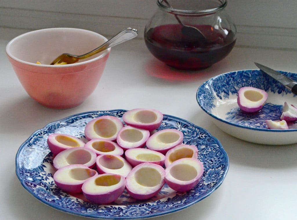 Halved pickled eggs on a blue plate with the yolks taken out.