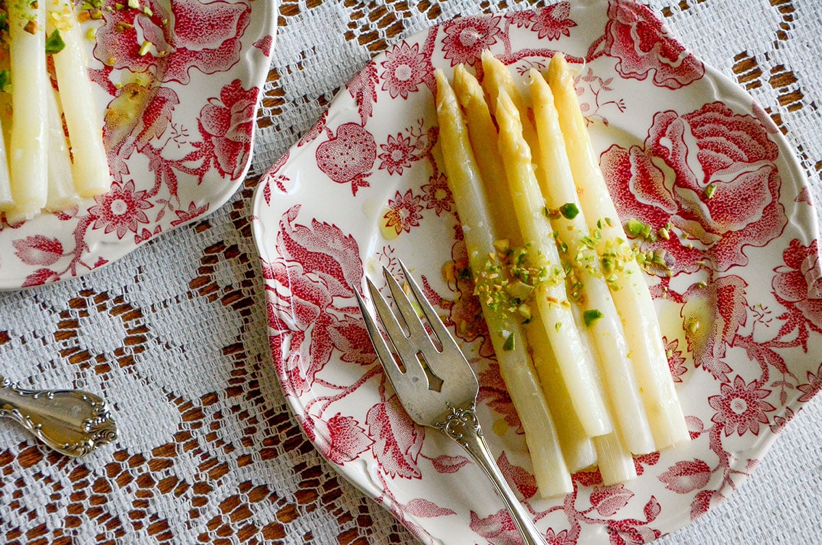 White asparagus with pistachios on a pink and white plate