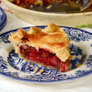 Piece of strawberry rhubarb pie on a blue and white plate