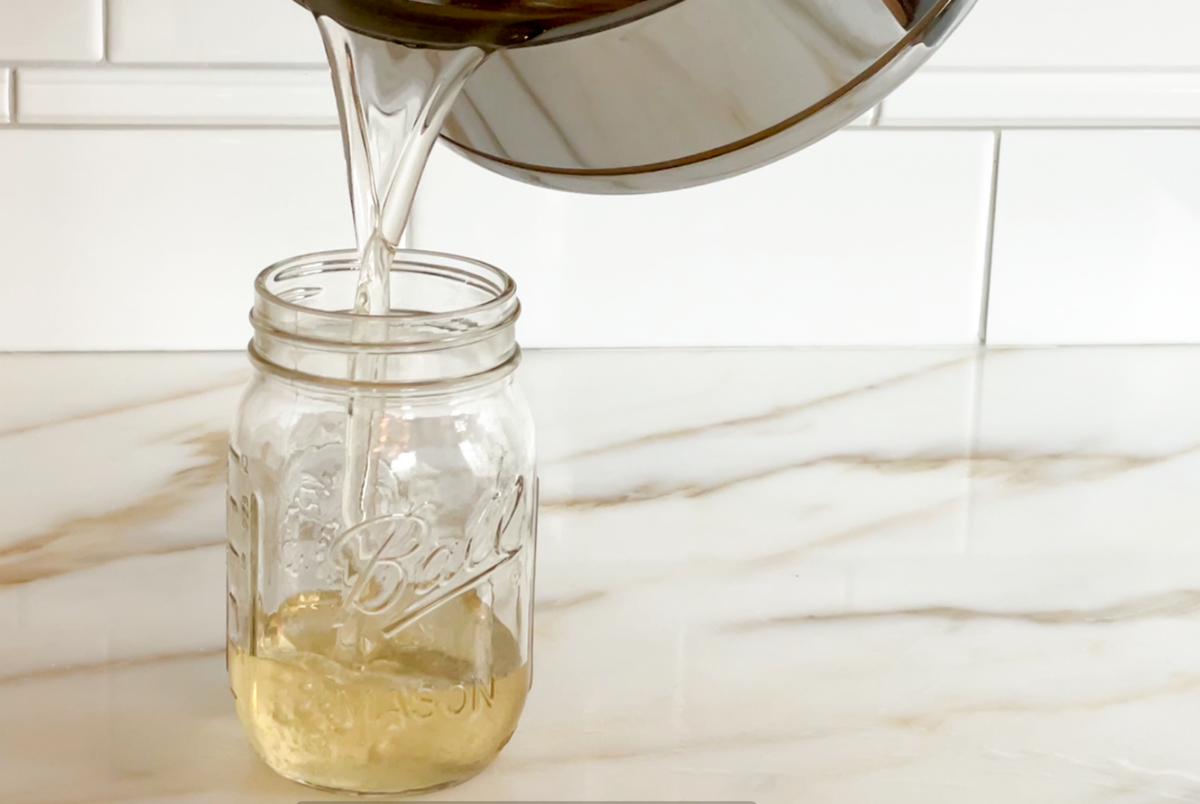 Simple syrup being poured into a glass mason jar from a pot